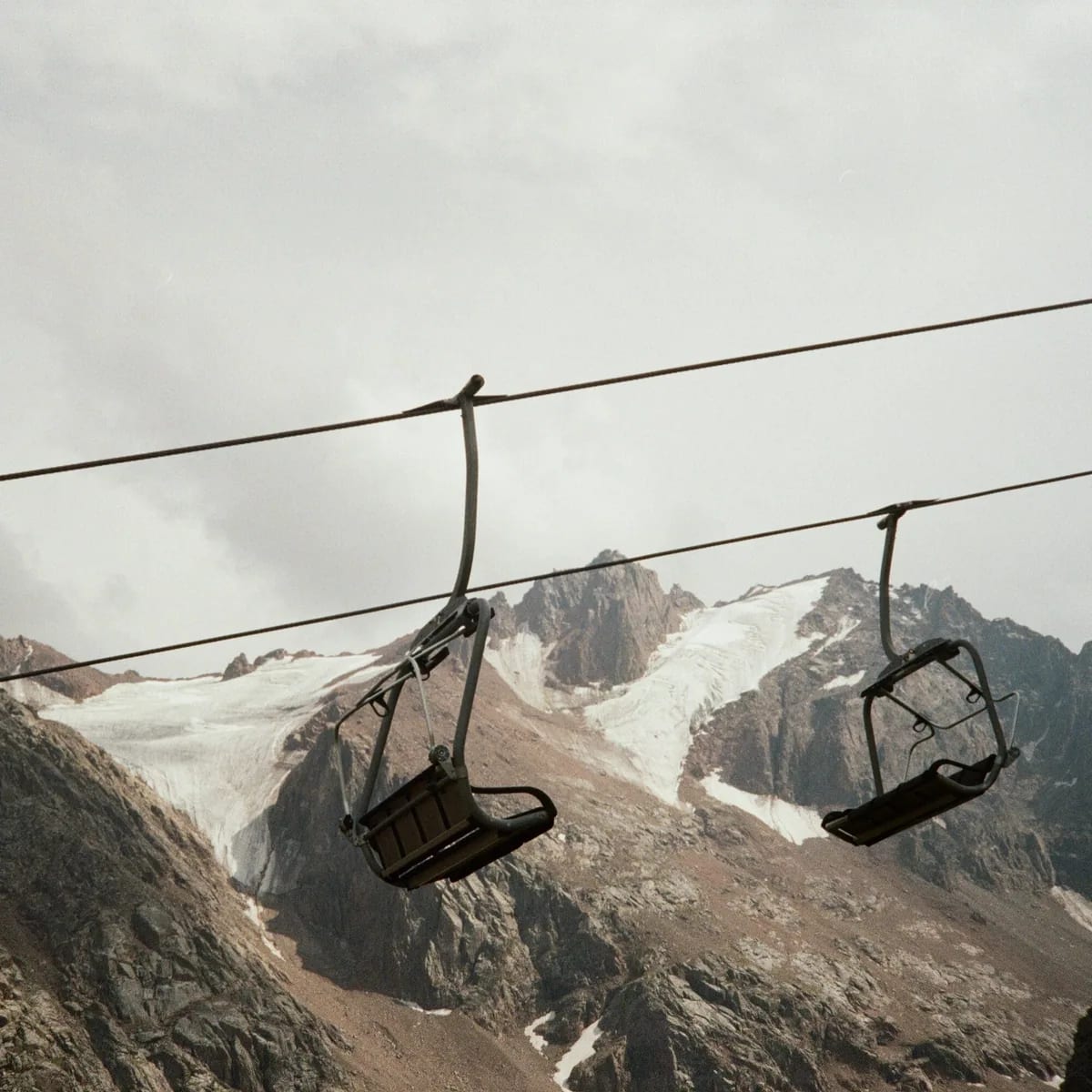 Ski lift chairs hang in front of mountains, Almaty