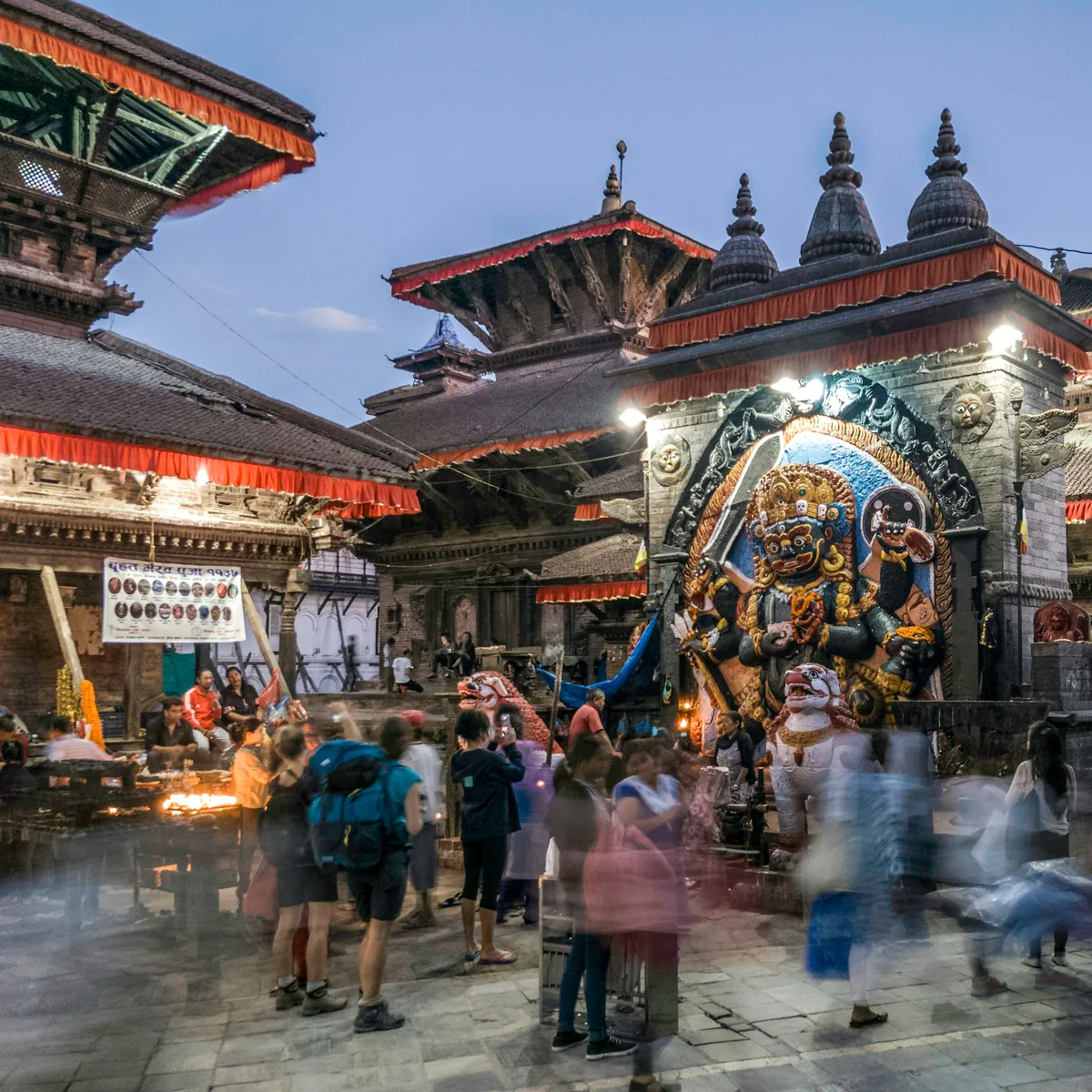 People standing in front of religious statue under blue sky, Nepal