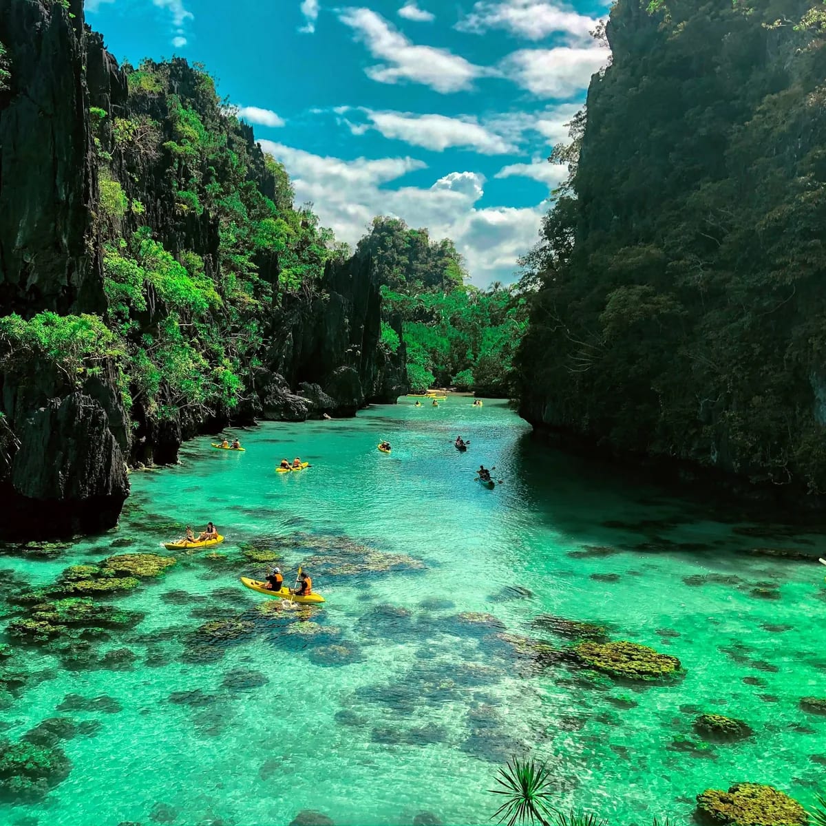 A group of people in a body of water surrounded by large rocks, Philippines