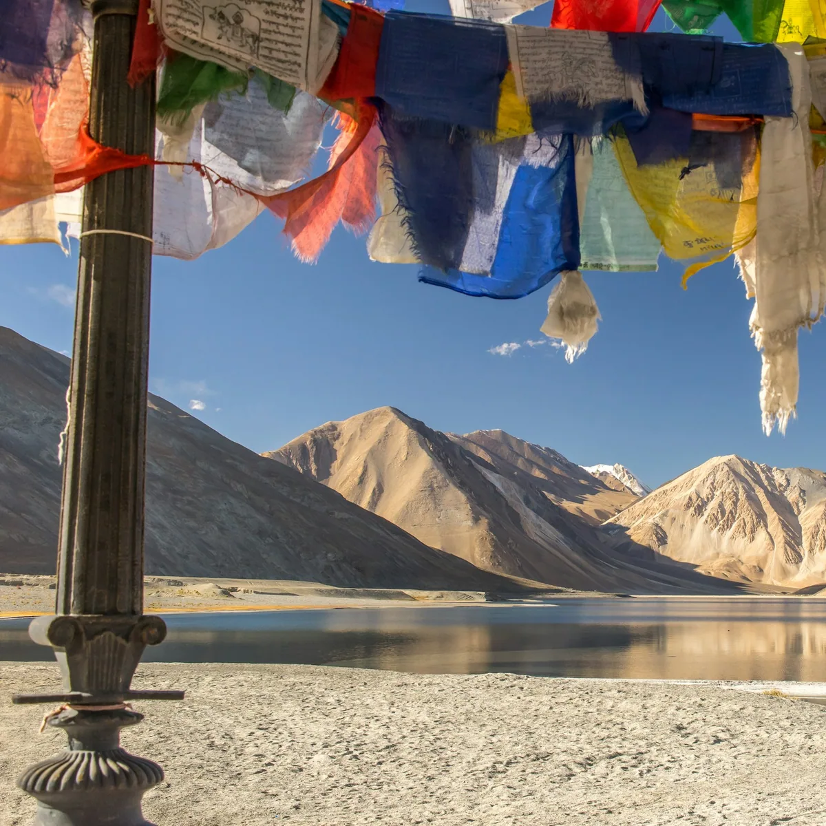 Blue yellow and red textile on gray sand near lake and moun…, Ladakh