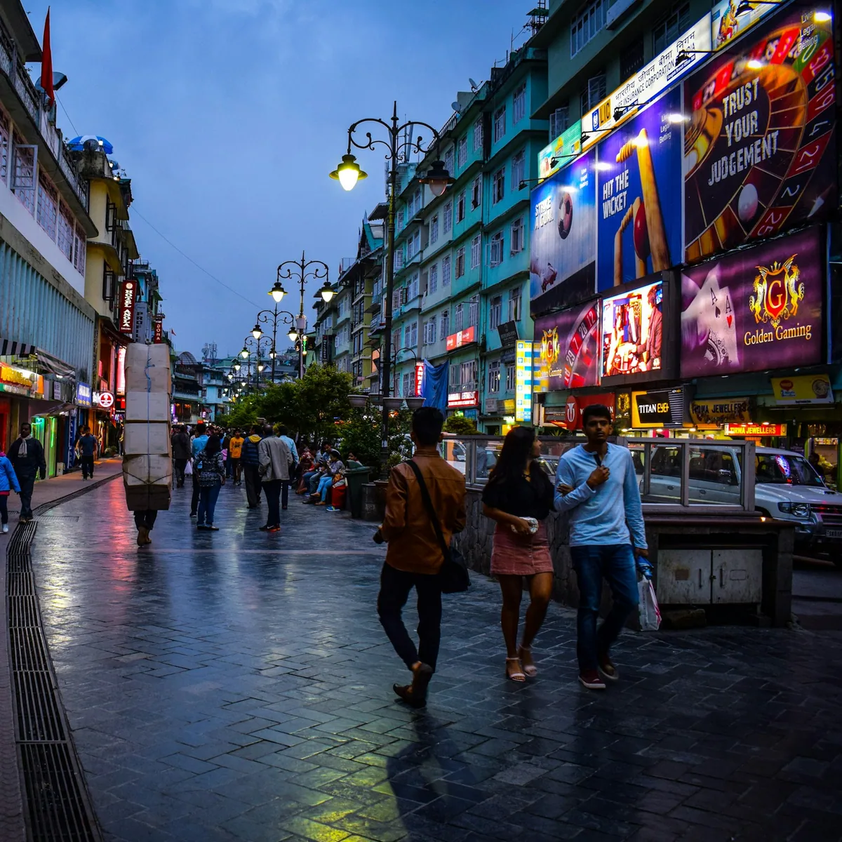 A group of people walking down a street next to tall buildings, Sikkim